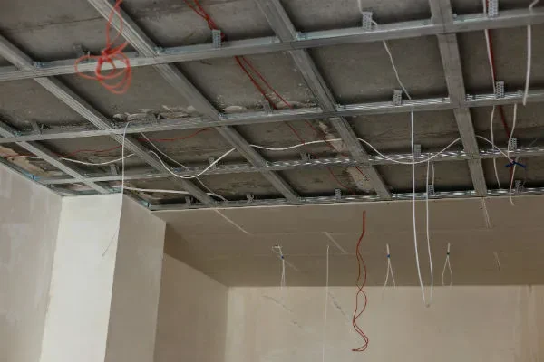Ossature métallique d’un faux plafond avec fils électriques visibles avant la pose des plaques.
