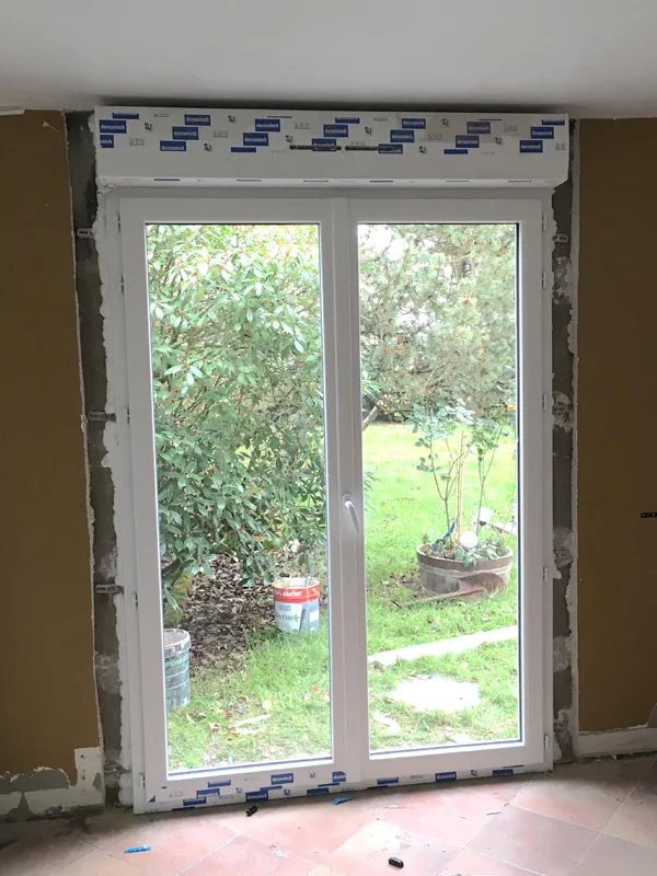 Baie vitrée posée dans une ouverture de villa, avec raccords de maçonnerie encore apparents.