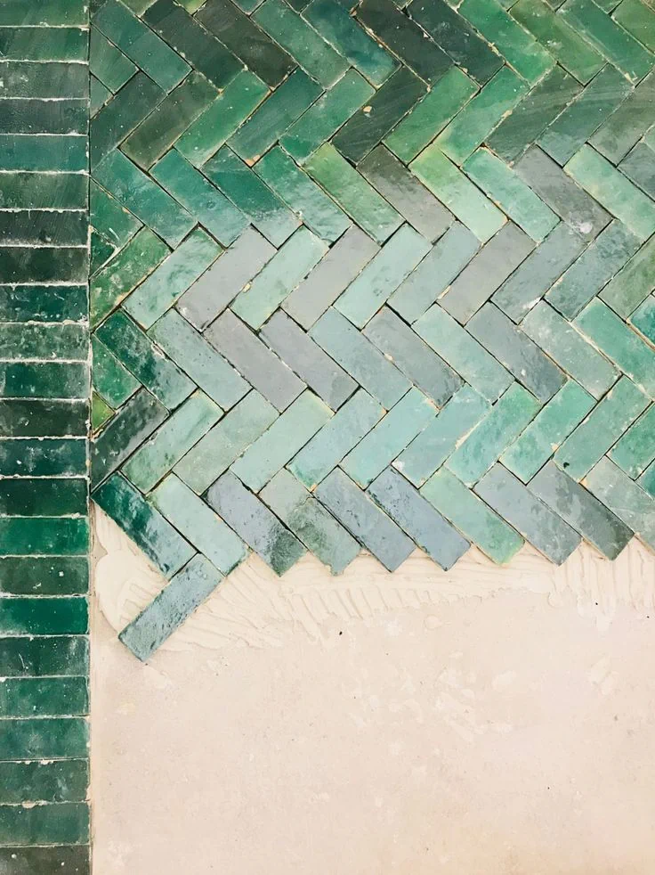Carreaux émaillés verts posés en chevrons, avec une partie du revêtement encore inachevée.